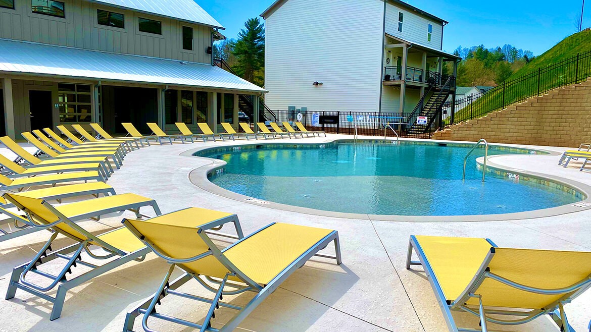 Another image of the pool with bright yellow lounge chairs around it.